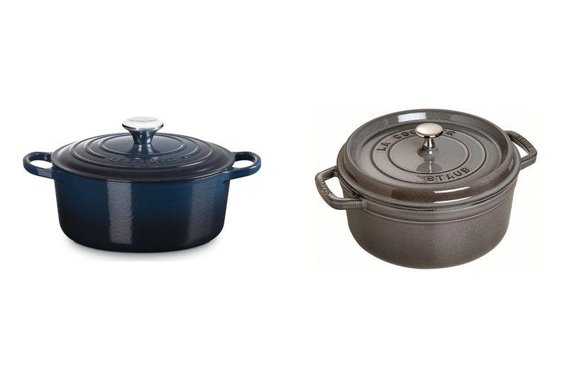 A navy Le Creuset Signature round casserole next to a graphite Staub round cocotte